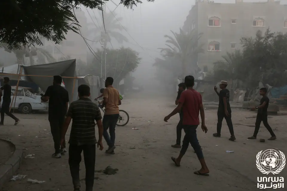 People on a street with damaged buildings and debris in Deir al-Balah, Gaza, August 2024.